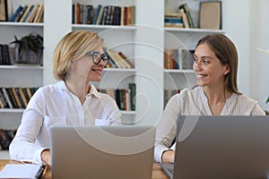 Two female collegues working with laptop and discussing new project photo
