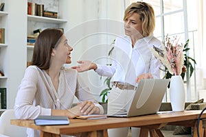 Two female collegues working with laptop and discussing new project photo