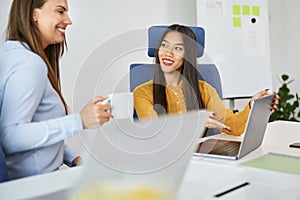 Two female coworkers talking at office