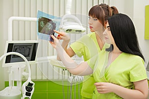Two female dentist in dental office examining patient teeth