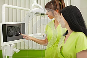 Two female dentist in dental office examining patient teeth