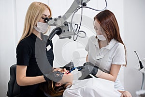 Two female dentists checking up patient teeth with dental tools at dental clinic office