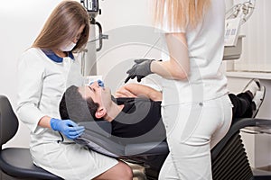 Two female dentists treating patient teeth with dental tools at dental clinic office