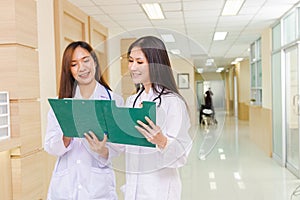 Two female doctors discussed together about a patient case with clipboard and stood