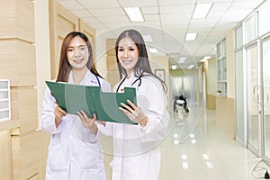 Two female doctors discussed together about a patient case with clipboard and stood