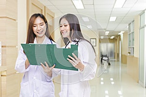 Two female doctors discussed together about a patient case with clipboard and stood
