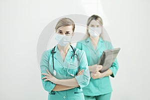 Two female doctors in medical masks looking at the camera. Stethoscope on neck