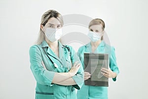 Two female doctors in medical masks looking at the camera. Stethoscope on neck