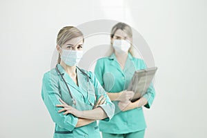 Two female doctors in medical masks looking at the camera. Stethoscope on neck