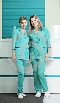 Two female doctors or nurses looking at the camera. In the hospital reception