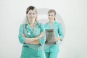 Two female doctors or nurses looking at the camera. Stethoscope on the neck