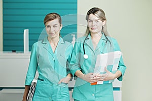 Two female doctors or nurses looking at the camera. Stethoscope on the neck