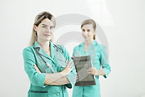 Two female doctors or nurses looking at the camera. Stethoscope on the neck