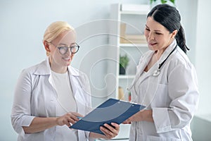 Two female doctors reading the medical history and looking positive