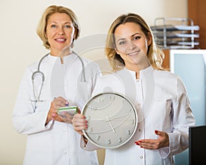 Two female doctors showing time in clock