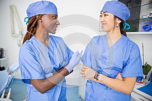 Two female doctors talk in a clinic during work, colleagues of different ethnicities