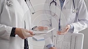 Two female doctors are using a tablet computer while standing and discussing health treatment in a hospital. Medicine