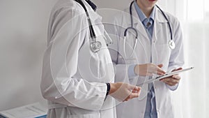 Two female doctors are using a tablet computer while standing and discussing health treatment in a hospital. Medicine