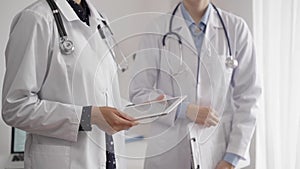 Two female doctors are using a tablet computer while standing and discussing health treatment in a hospital. Medicine