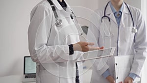 Two female doctors are using a tablet computer while standing and discussing health treatment in a hospital. Medicine