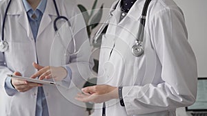 Two female doctors are using a tablet computer while standing and discussing health treatment in a hospital. Medicine