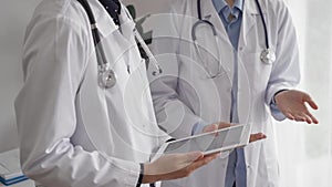 Two female doctors are using a tablet computer while standing and discussing health treatment in a hospital. Medicine