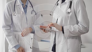 Two female doctors are using a tablet computer while standing and discussing health treatment in a hospital. Medicine