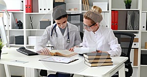 Two female doctors working with medical directory.