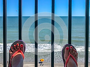 Two female feet with a pedicure against the background of the ocean beachfront boardwalk Myrtle Beach South Carolina