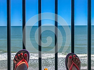 Two female feet with a pedicure against the background of the ocean beachfront boardwalk Myrtle Beach South Carolina