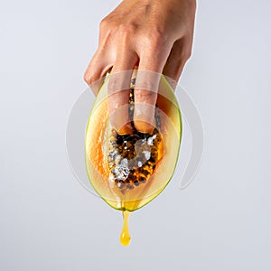 Two female fingers in papaya fruit with a dripping honey. Sex concept