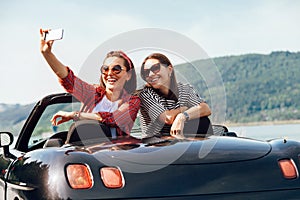 Two female freinds take a selfie photo in cabriolrt car during t