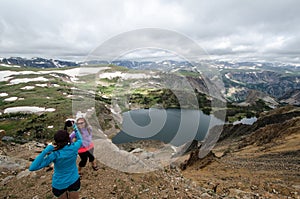 Two female friends 20s take pictures of each other at an overlook in the mountains of Montana