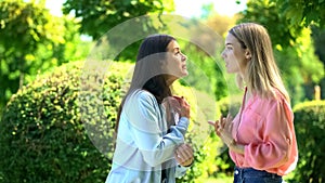 Two female friends arguing outdoors, relations confrontation, communication