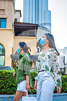 Two female friends Asian woman wearing face mask in outdoors shopping mall