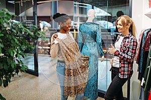 Two female friends choosing dresses, shopping