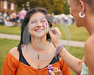 Two Female Friends Decorating Faces With Glitter At Summer Music Festival 