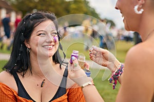 Two Female Friends Decorating Faces With Glitter At Summer Music Festival 