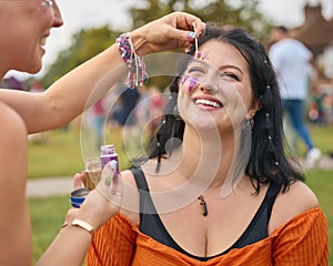Two Female Friends Decorating Faces With Glitter At Summer Music Festival 