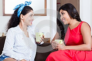 Two female friends drinking tea or coffee indoors