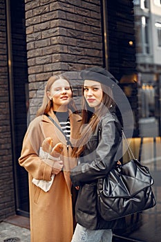 Two female friends in fashion clothes standing on the street