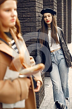 Two female friends in fashion clothes standing on the street