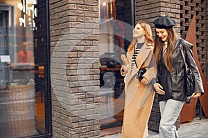 Two female friends in fashion clothes walking on the street