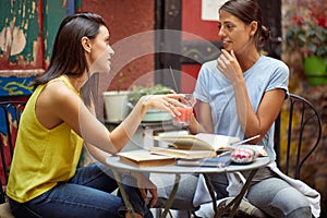 Two female friends having a chit-chat in outdoor cafe