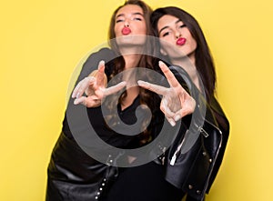 Two female friends having fun together, showing peace gesture