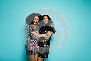 Two female friends hugging over blue background