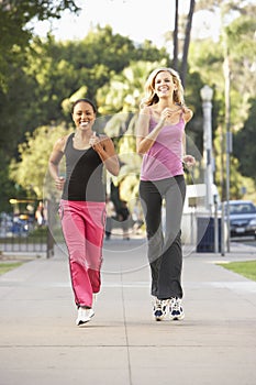 Two Female Friends Jogging On Street