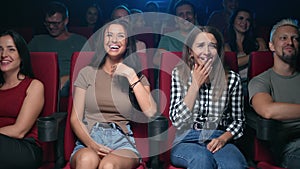Two female friends laughing having positive emotion at comedian movie sitting on armchair row