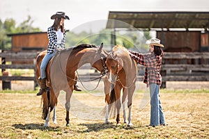Two female friends on a ranch are getting ready for a horse ride