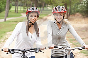 Two Female friends riding bikes in park